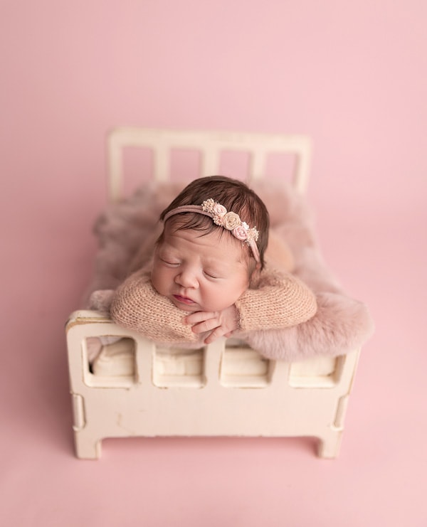 Newborn baby on a tiny bed, pink baby photoshoot, Austin newborn photographer