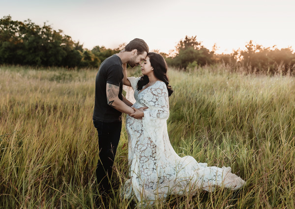 Couple at a open field with trees and hay bales captured by Austin Maternity photographer.