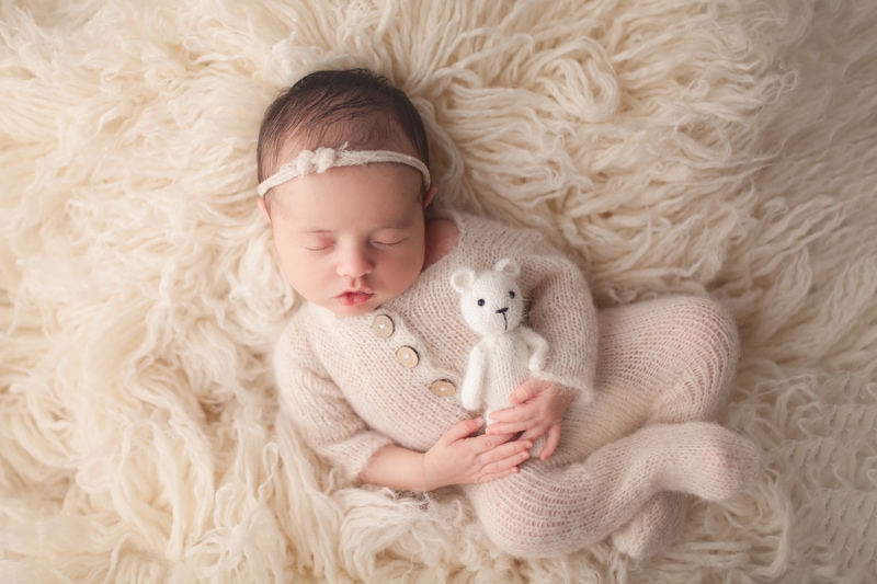 Baby holding a tiny teddy bear