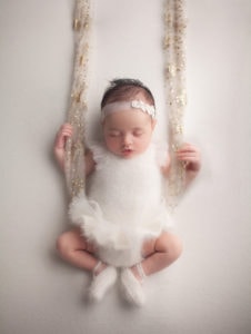 Newborn Photographers, a baby sits in a swing wearing ballerina outfit