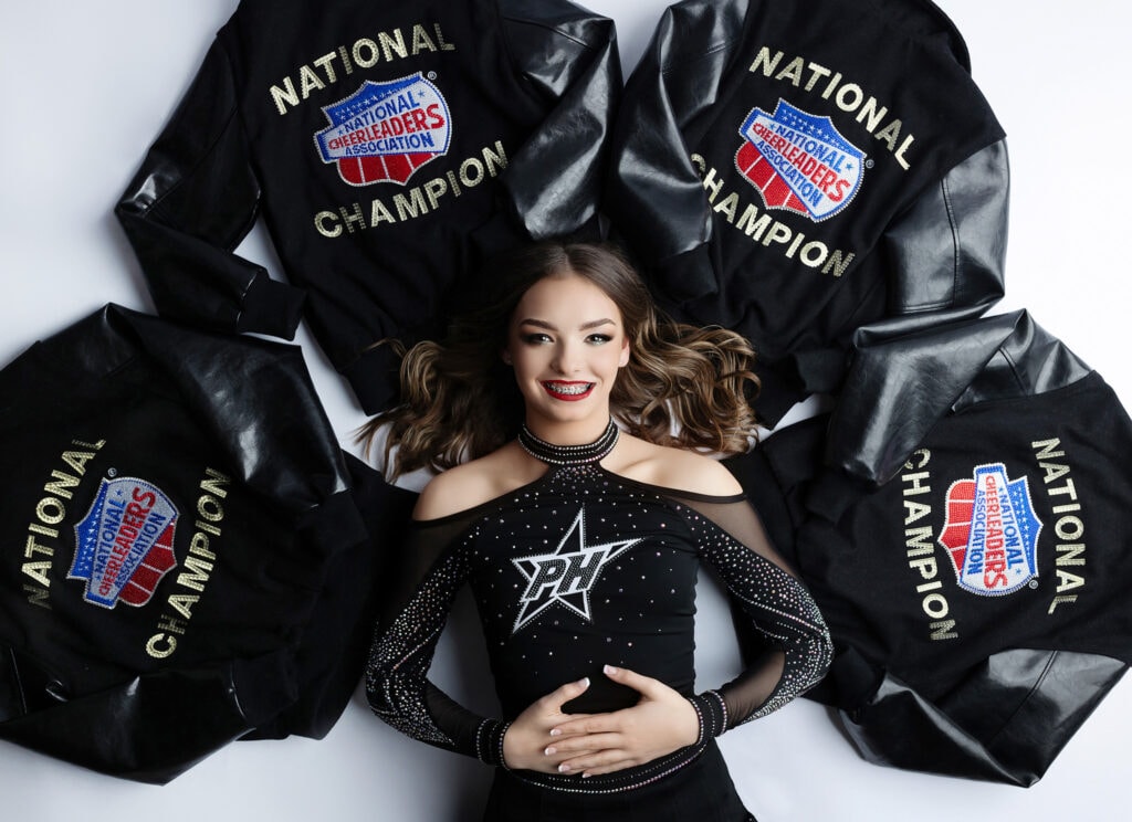 Belton powerhouse cheerleader laying on her national championship jackets.
