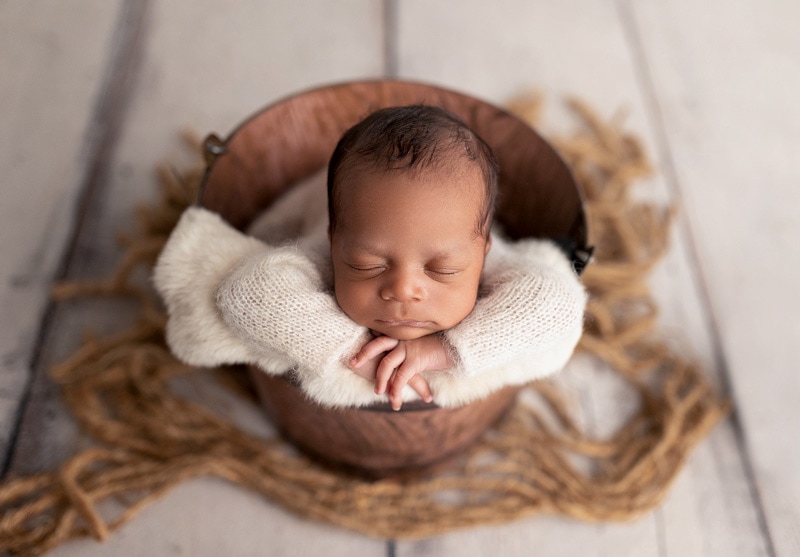 Newborn baby boy on a pooh bucket with a wood backdrop.